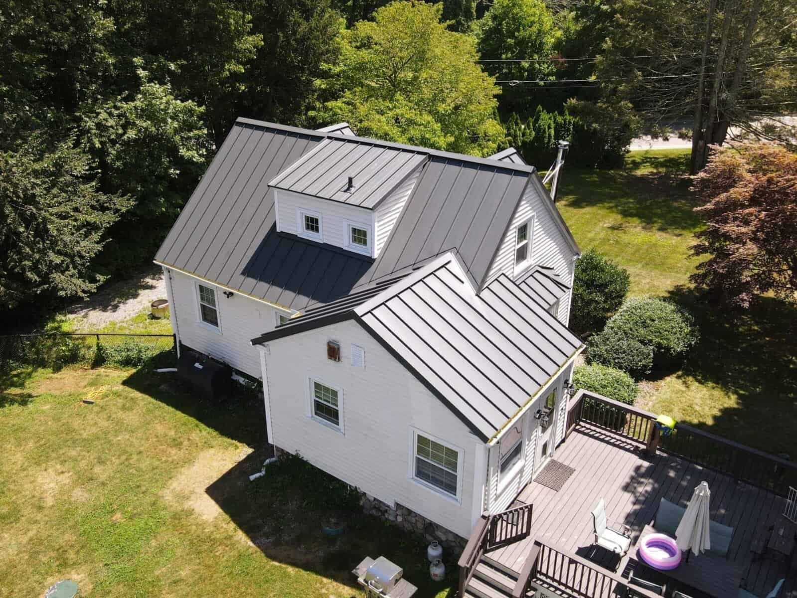 Metal roof on a white residential house with backyard