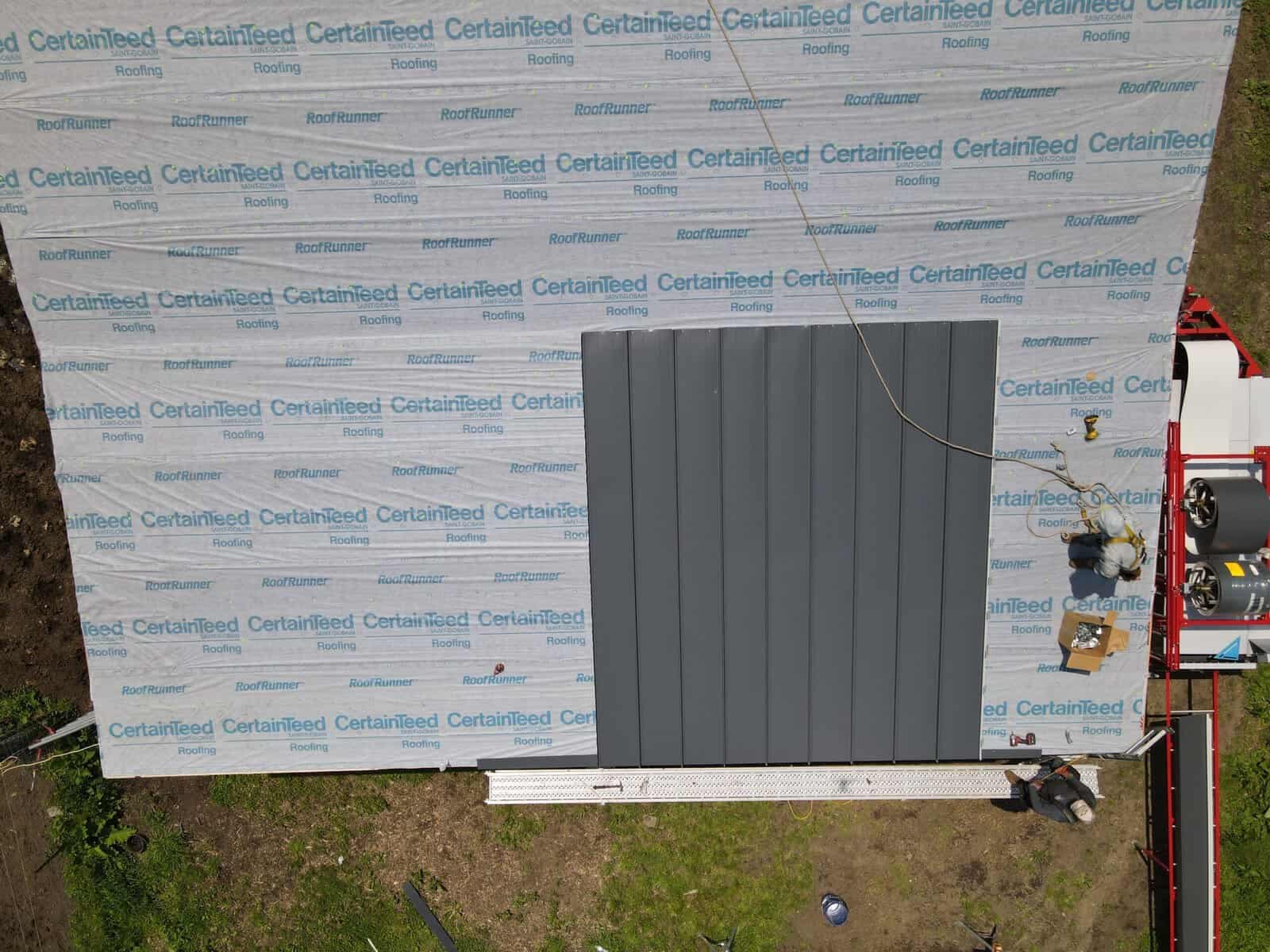 Synthetic underlayment being applied to roof deck