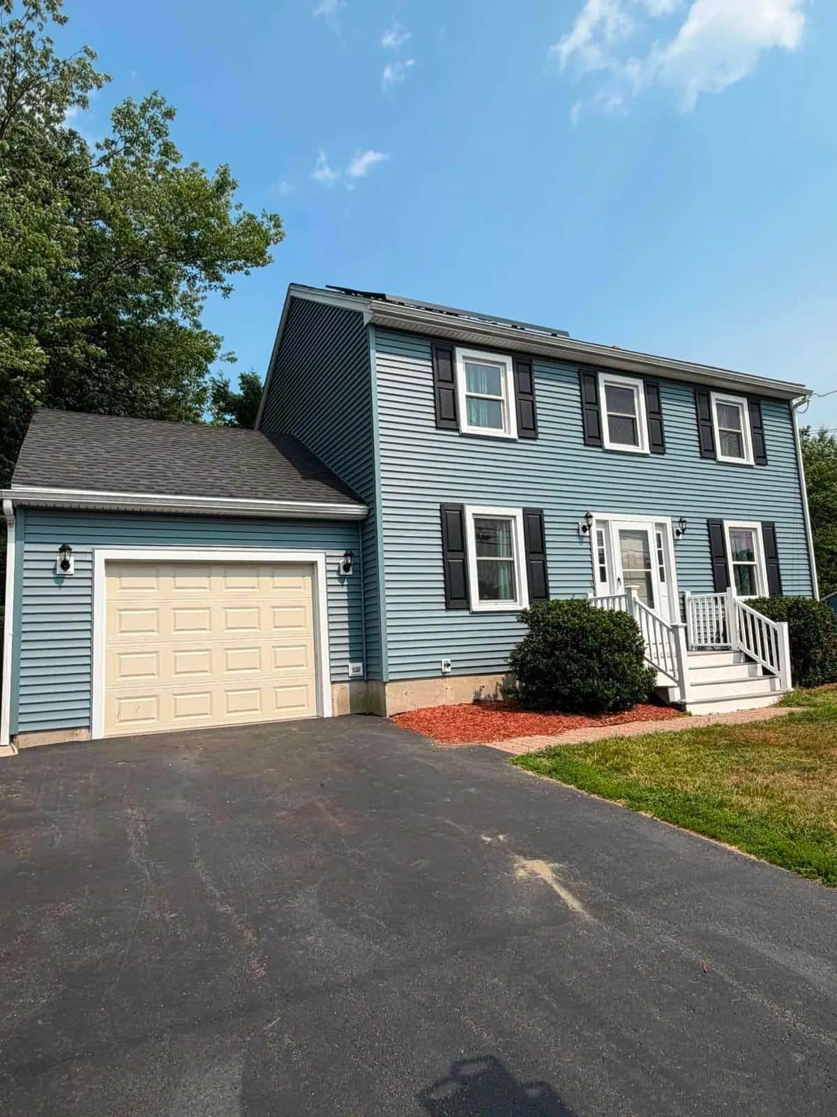 Colonial in Gardner, MA with new blue clapboard siding, seen from the driveway with the garage