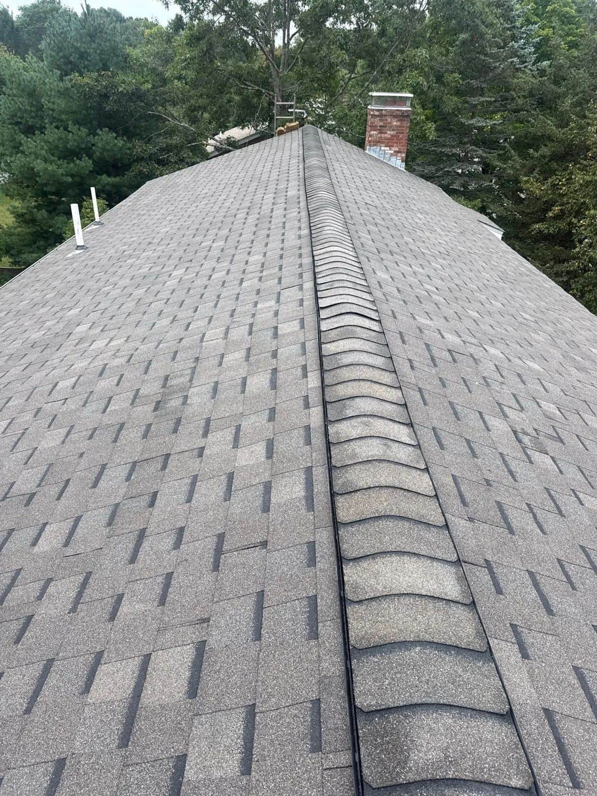 View up a new gray shingle roof toward the ridge in Medfield, MA