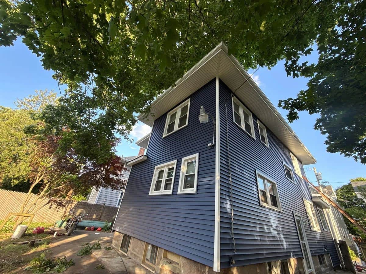 Two-story home in New Bedford, MA with new blue clapboard siding and white window trim