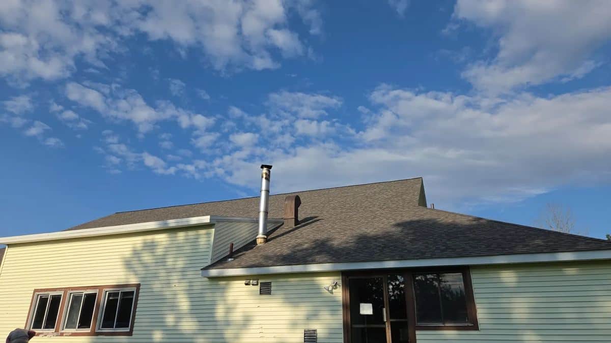 Yellow home in Rutland, MA with a new brown architectural shingle roof under a blue sky