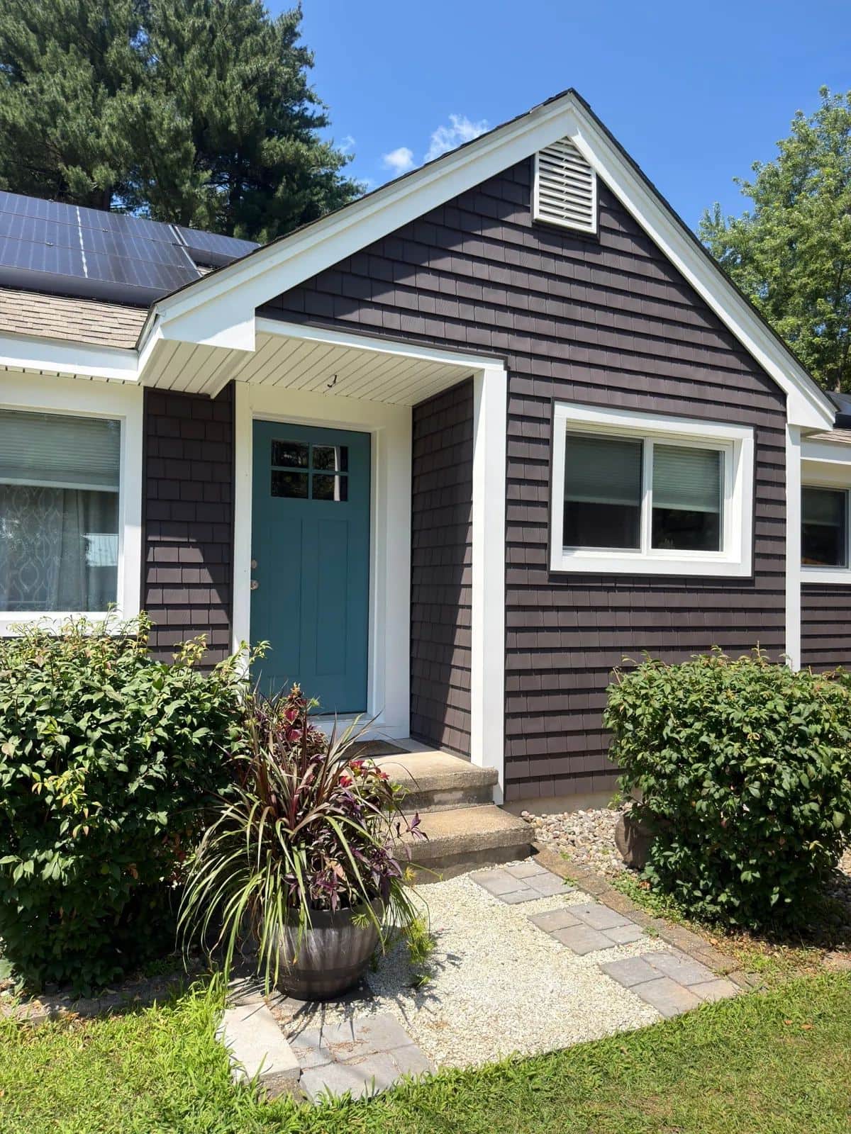 Turners Falls, MA ranch with faded tan vinyl siding before, and new dark gray shake-style siding with crisp white trim and a blue front door after