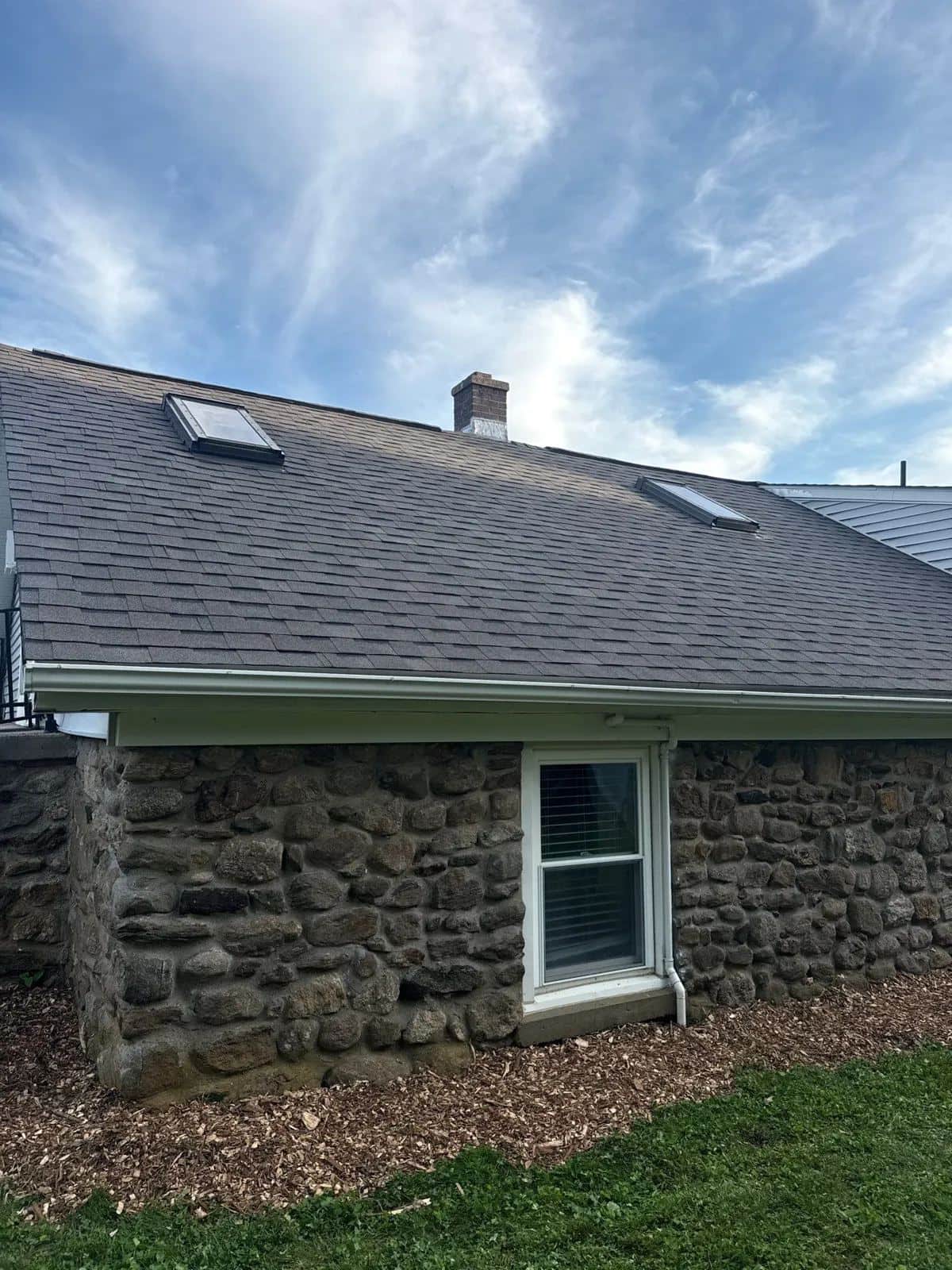 Watertown, CT stone cottage with an aged, stained light gray shingle roof before, and a new charcoal architectural shingle roof after