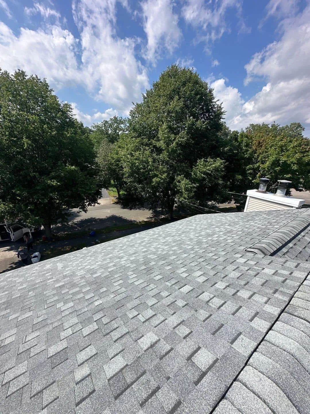 New gray shingle roof in West Haven, CT with trees behind