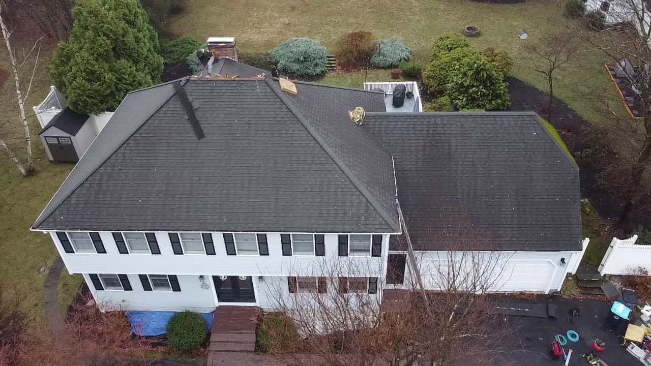 Massachusetts home during roof tear-off, with old shingles being removed