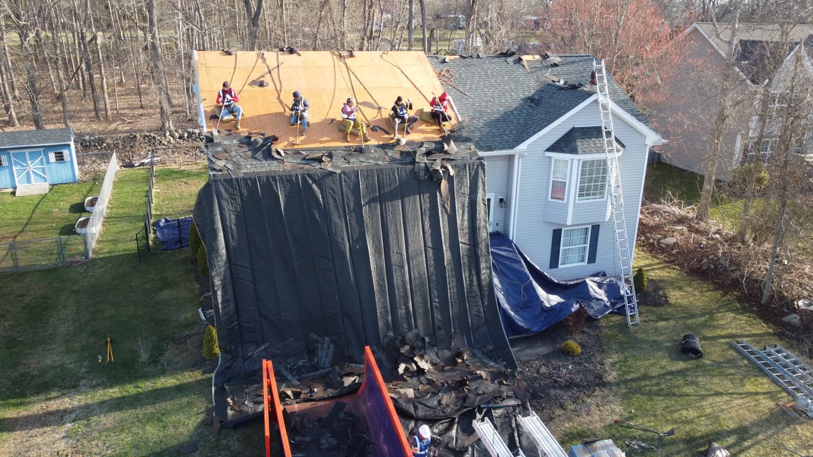 Global Roofing crew tearing off old shingles from a residential home — first stage of a 1-day roof replacement