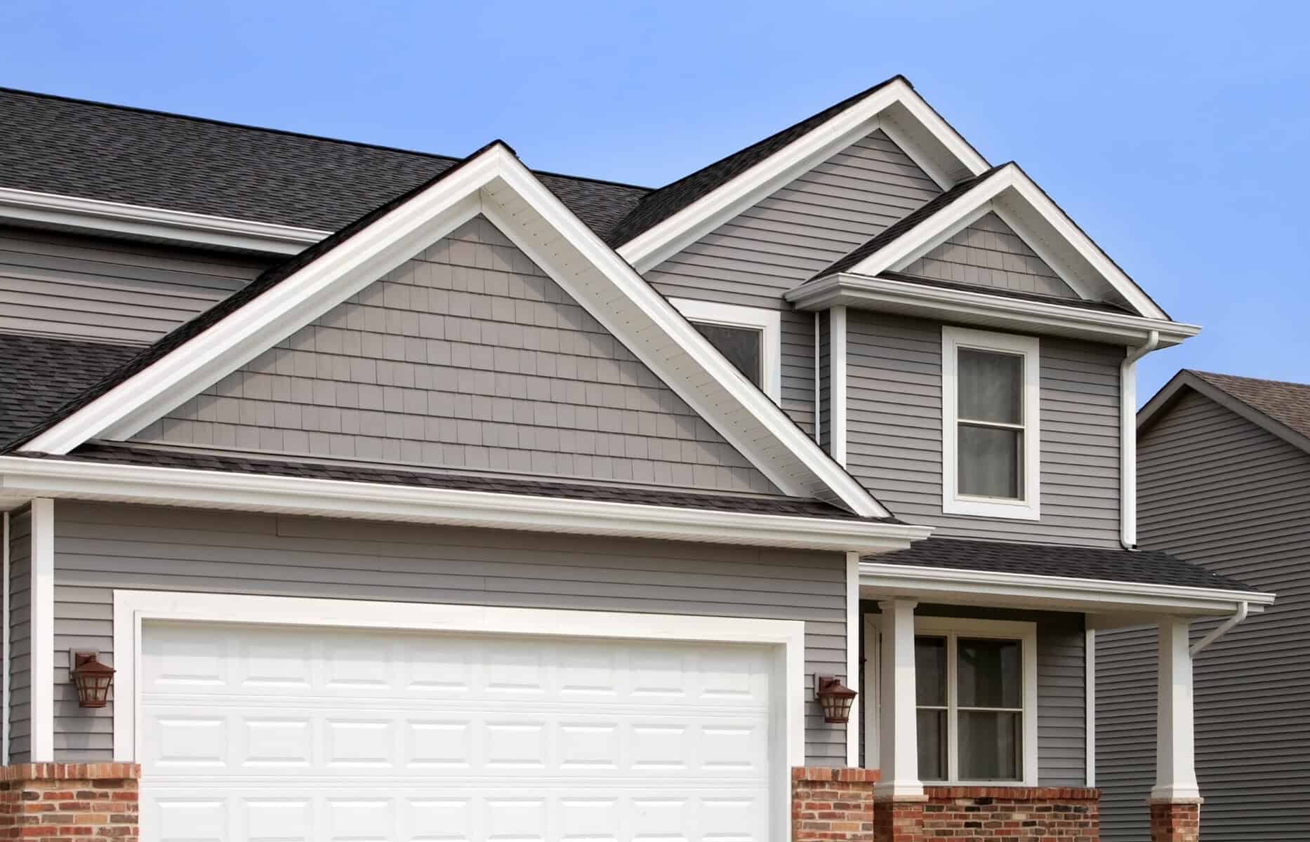 Roof of a modern house with gray siding and black shingles, showcasing professional residential roofing and exterior home improvement.
