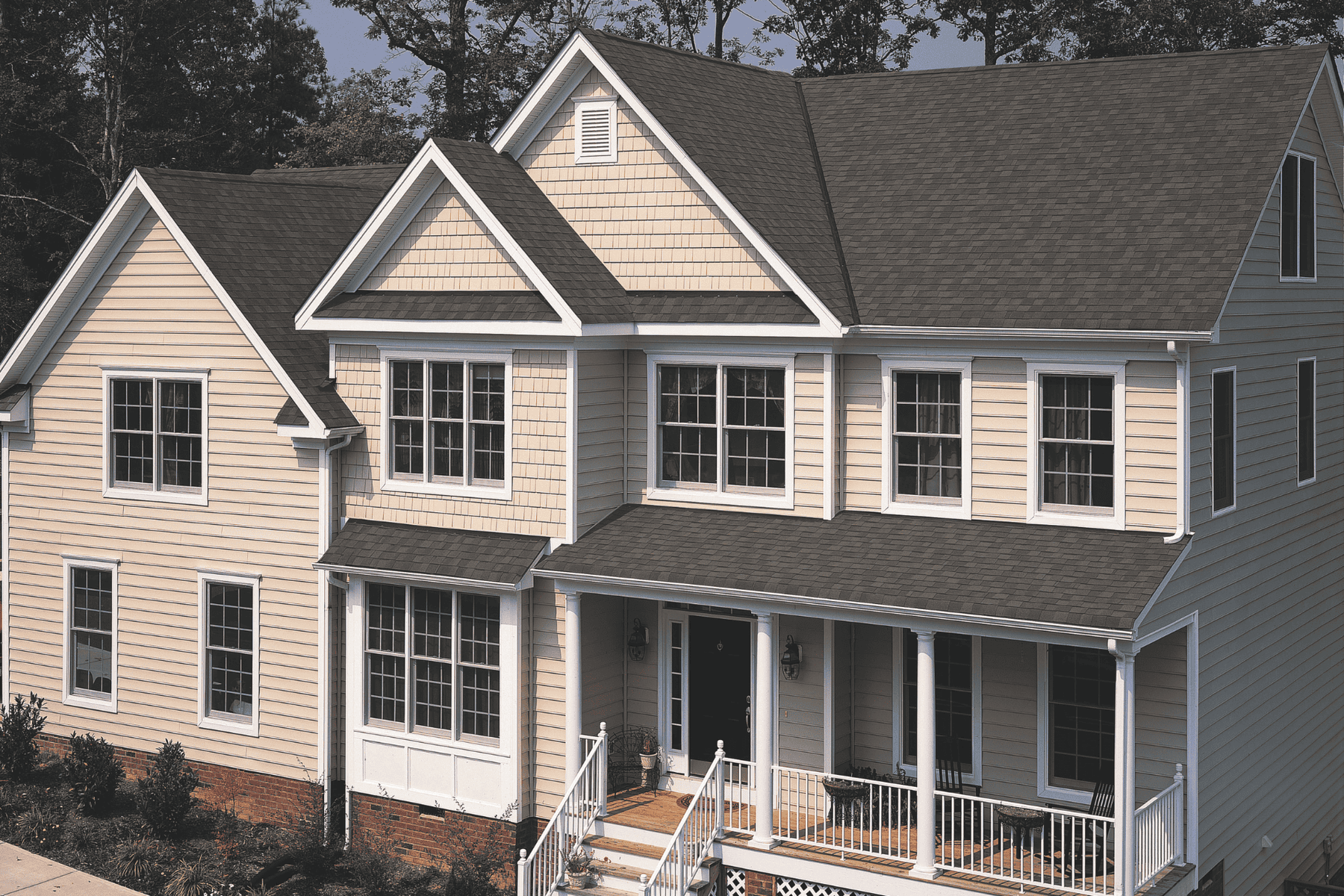 Beautiful siding and roofing details of a modern suburban home with a welcoming front porch and multiple windows.
