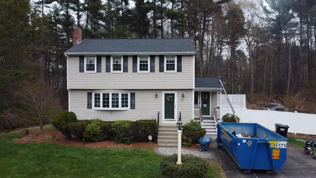 Roof of a modern two-story house with asphalt shingles in a suburban setting.