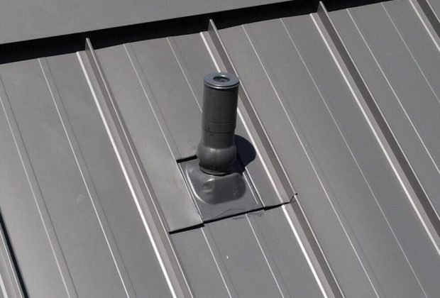 Metal roof vent pipe on a standing seam metal roof, essential for attic ventilation and weather resistance.
