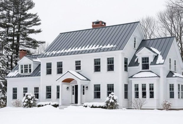 White modern house with metal roofing in snowy winter landscape.